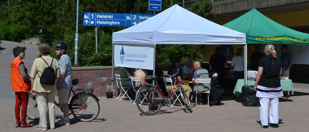 Kannelmäen seurakunnan ja soppatykki.fi:n katokset, ihmisiä ja polkupyöriä kesällä kaupungissa