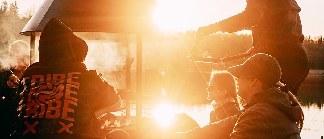 Nuoria aikuisia grillaamassa Porkkalan leirikeskuksessa auringonlaskua vasten.