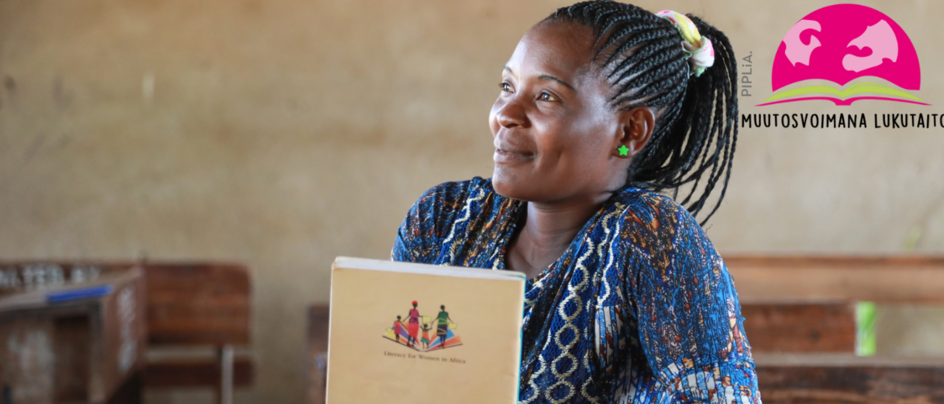 Afrikkalainen nuori nainen hymyilee kirja kädessä. Pipliaseuran logo Muutosvoimana lukutaito. Kuva: Pipliaseura