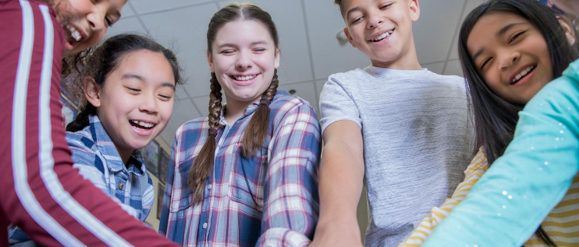 Ryhmä iloisia alakoululaisia koulun käytävällä.