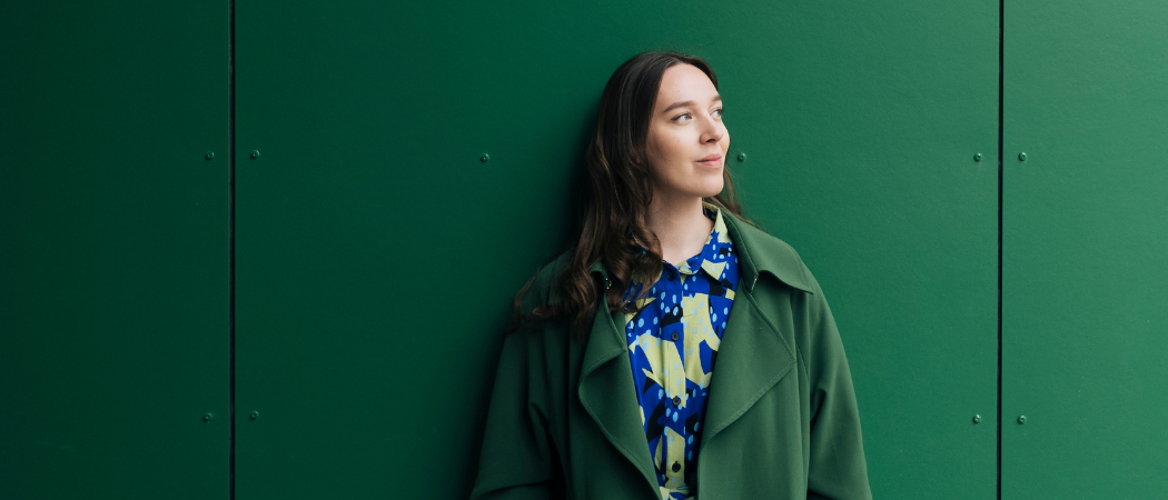 Nainen nojaa vihreää seinää vasten.