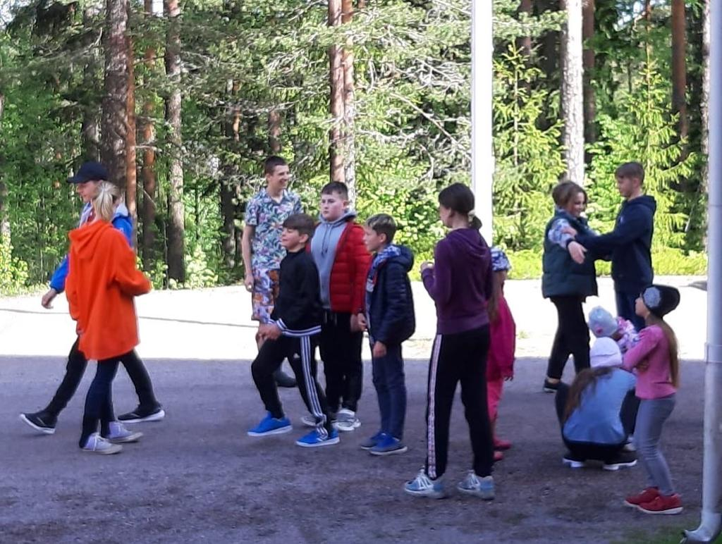 En barngrupp umgås utomhus vid en sportplan.