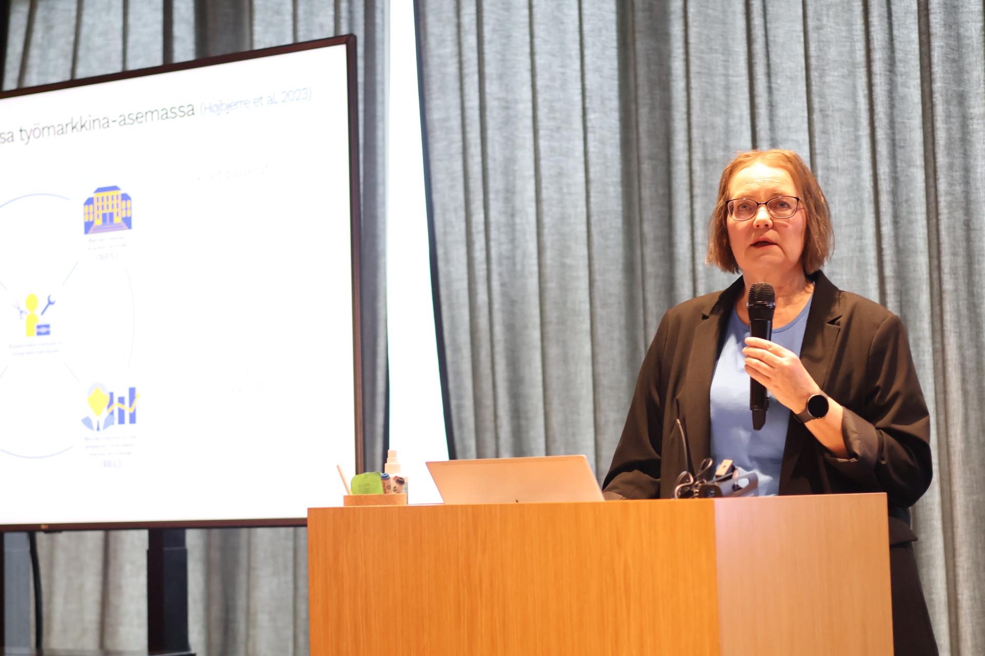 Puhuja puhuu mikrofoniin puhujakorokkeella.