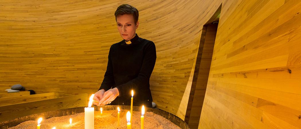 Pappi Nanna Helaakoski Kampin kappelissa kynttilöiden äärellä