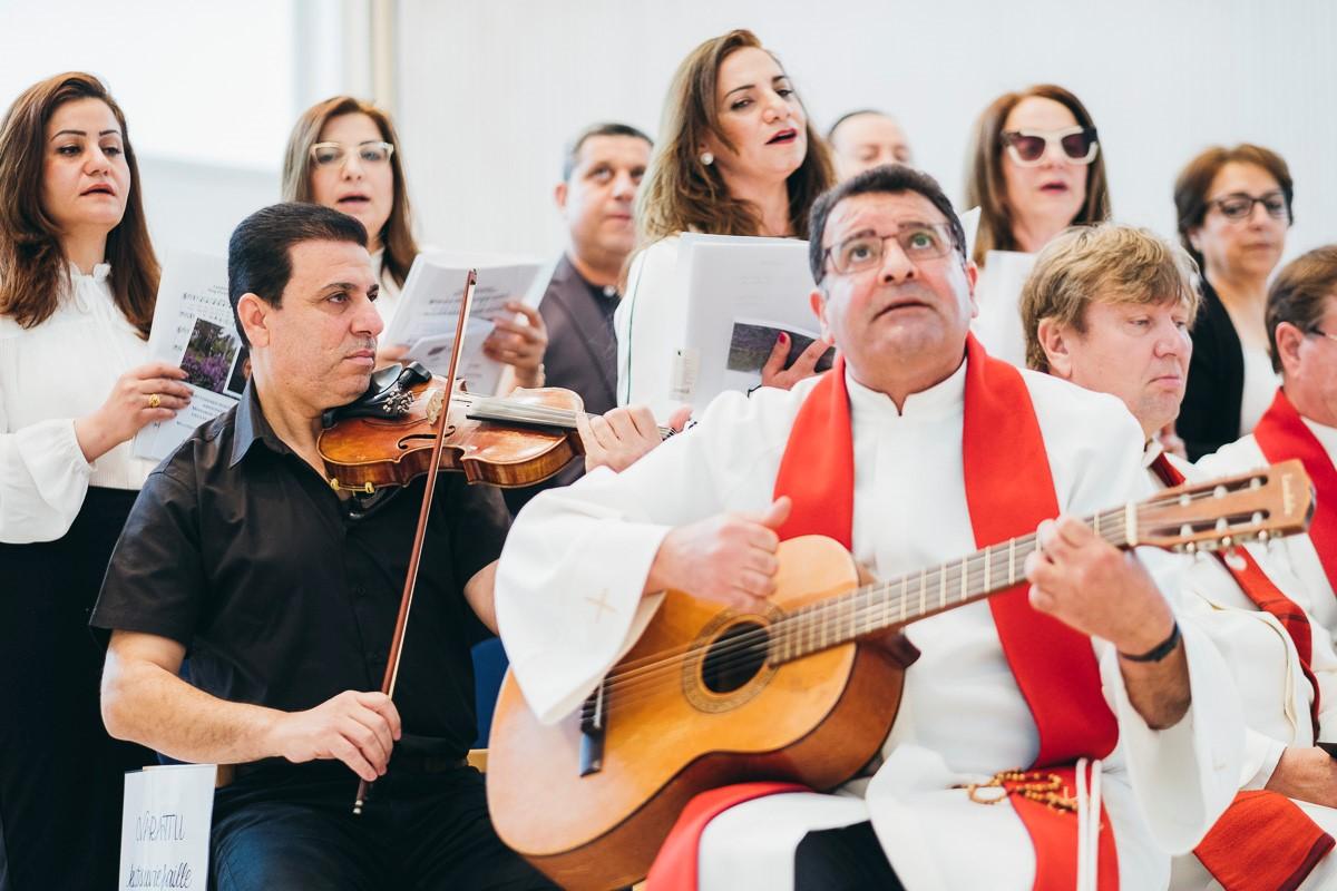 Arabiankielinen rauhankuoro laulaa Myllypuron kirkossa. Keskellä soittaa kitaraa Ramez Ansara