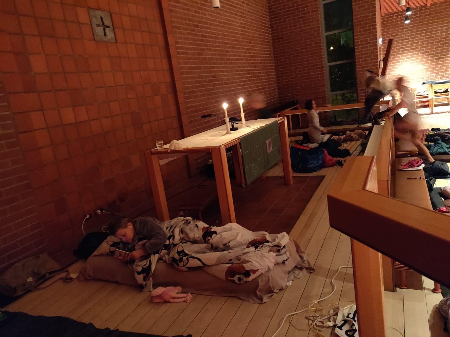 En flicka ligger på en madrass intill altaret i Matteuskyrkan.