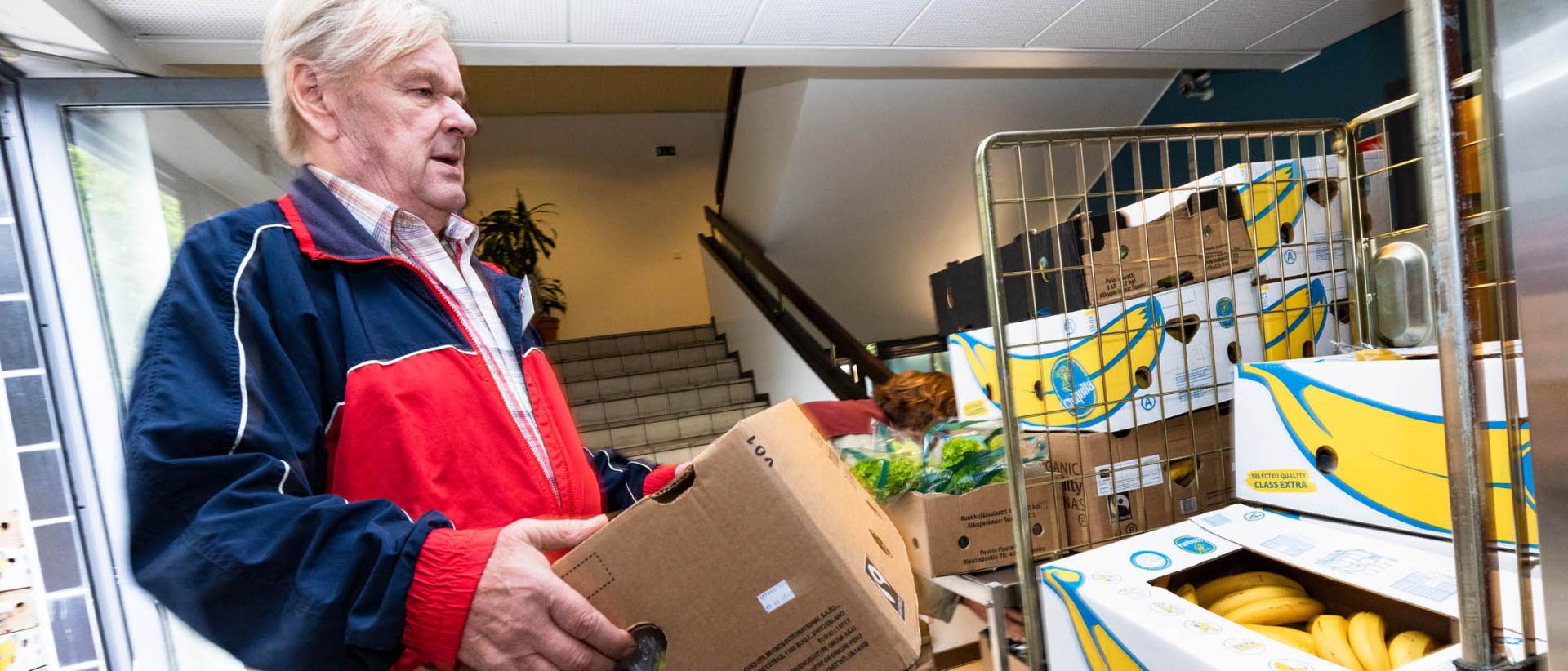 Hermannin diakoniatalon vapaaehtoistyöntekijä nostelee banaanilaatikoita