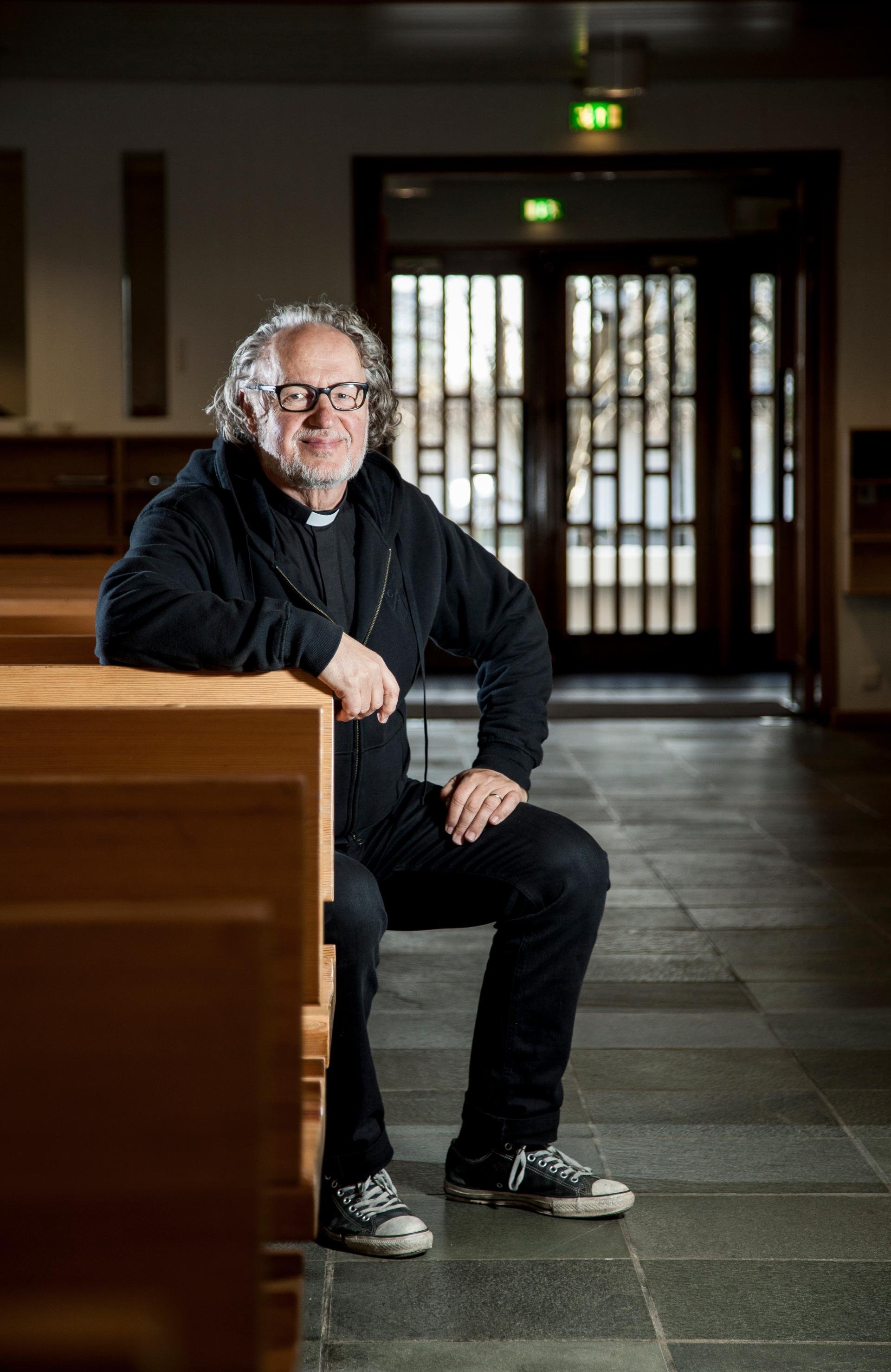 Munkkiniemen kirkkoherra Leo Glad istuu Munkkivuoren kirkon penkissä hymyillen