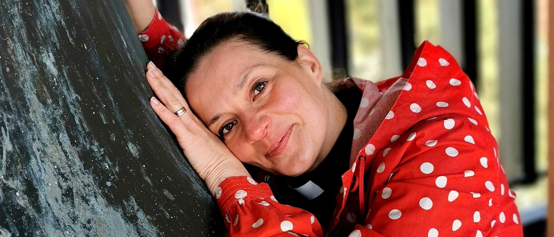 Lähikuva Emriikka Salosesta punavalkopilkullisessa puserossa nojaamassa Roihuvuoren kirkon kelloon Kuva: Marko Anttila