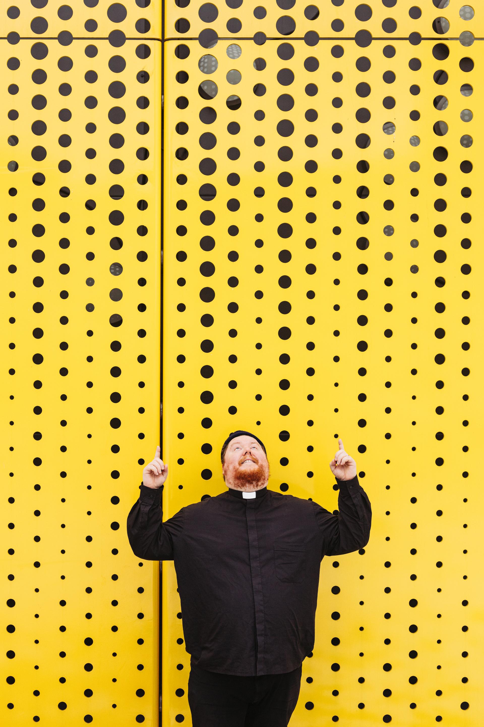 Pappi Visa Viljamaa keltaista seinää vasten katse ylöspäin