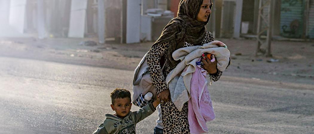 Syyrialainen äiti pakenee lapsensa kanssa Turkin pommituksia Ras-al-Ain kaupungissa Koillis-Syyriassa. Kuva: AFP