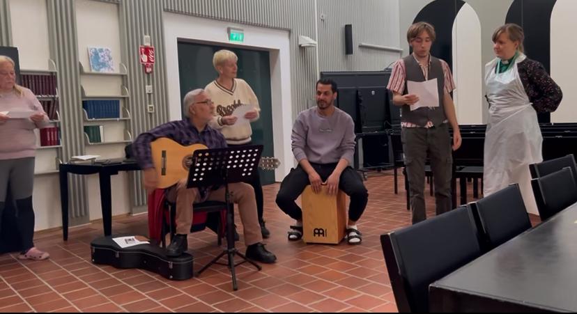 Muusikoita seurakuntasalissa. Kitaristi, rumpali ja laulajia.