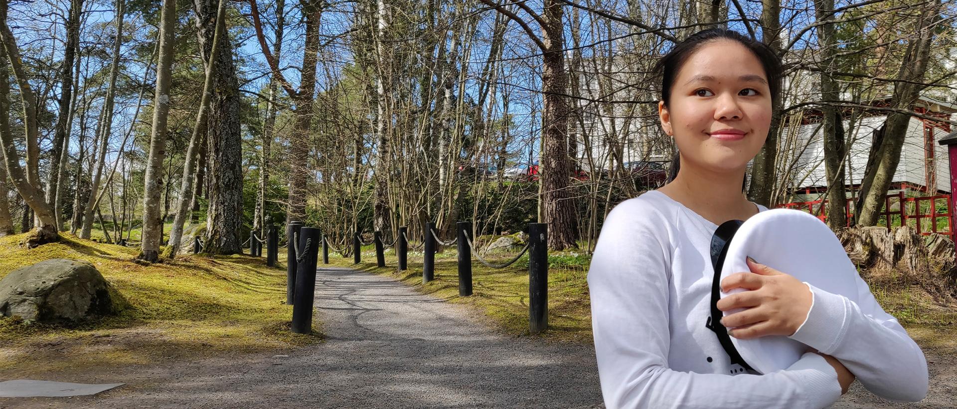 Ylioppilas Maiju Lehtivaara istumassa japanilaisen puutarhan portailla Roihuvuoressa