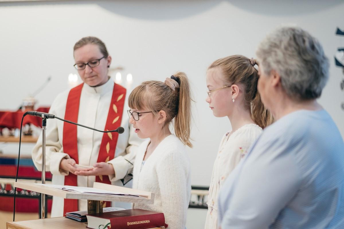 Jenni Kallio ja eri-ikäisi' seurakuntalaisia lukemassa yyhteistä esirukousta. Kuva: Antto Rintala