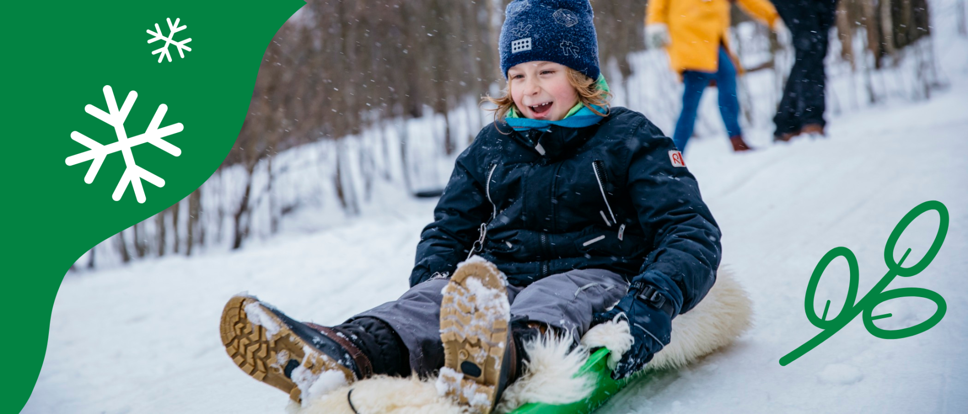 Lapsi laskee pulkalla m&auml;ke&auml; talvisessa maisemassa