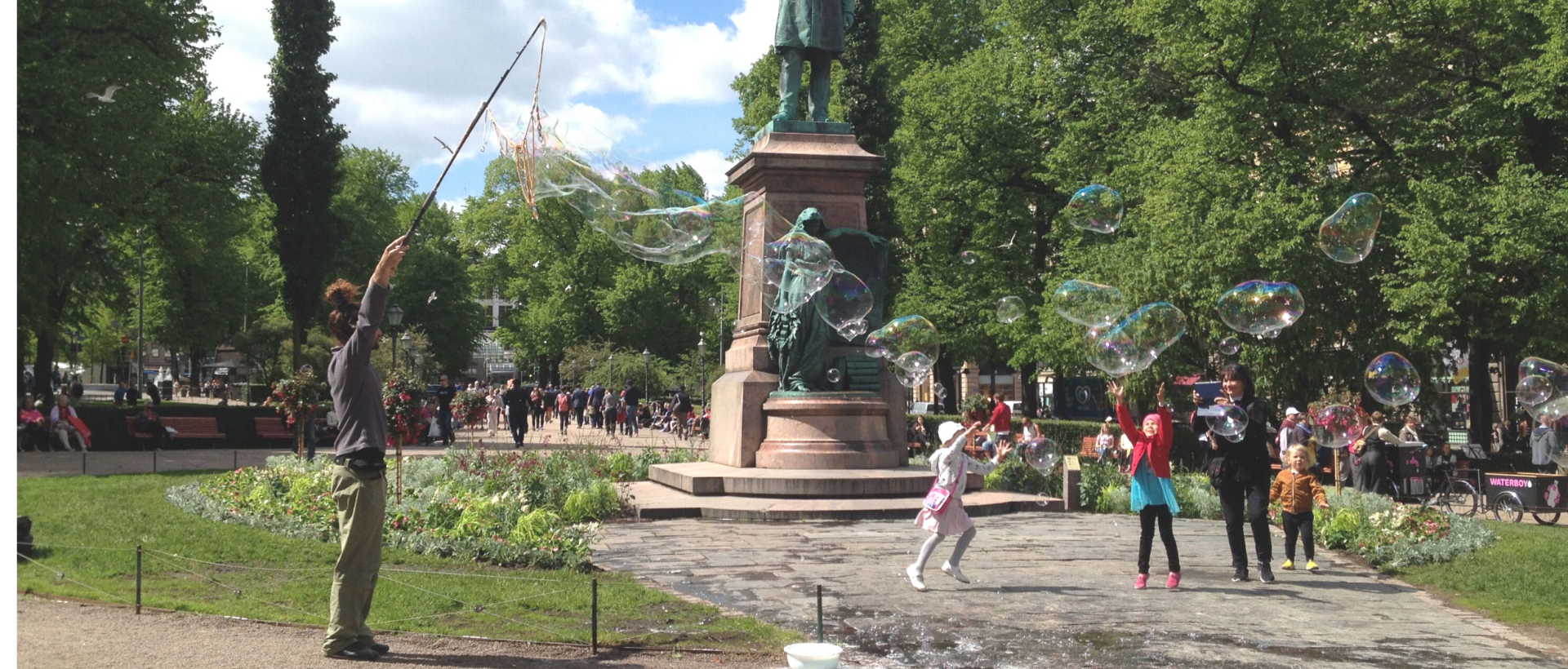 Barn jagar bubblor vid Runebergs staty