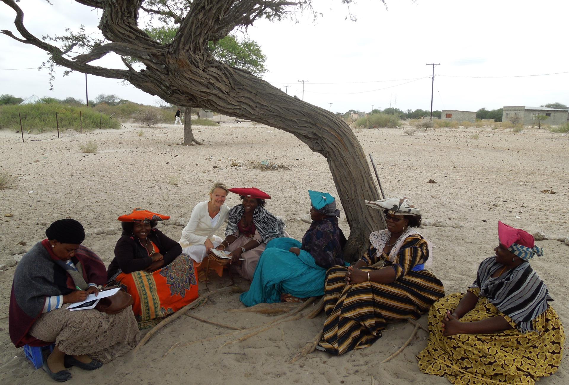 Tiina Harju vierailulla Rakopsin seurakunnassa Botswanassa. Kuvassa Tiina Harju istuu ulkona puun alla viiden paikallisen luterilaisen seurakunnan työntekijän kanssa.