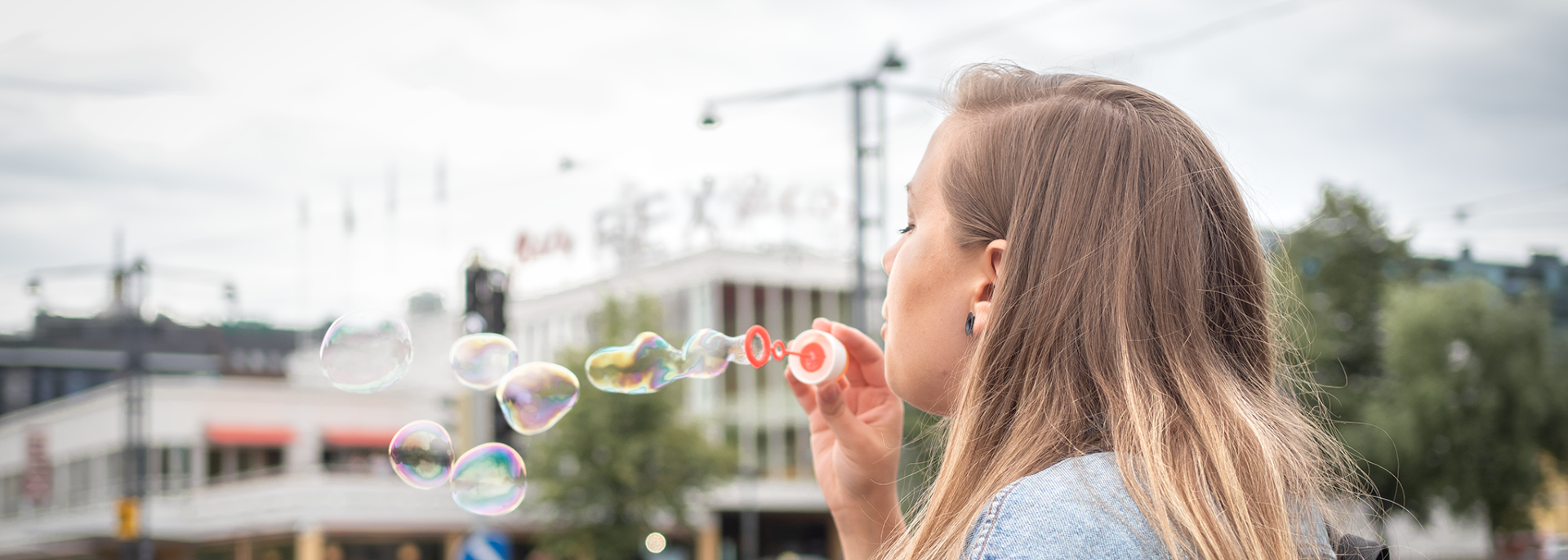 En flicka blåser såpbubblor på en gata.