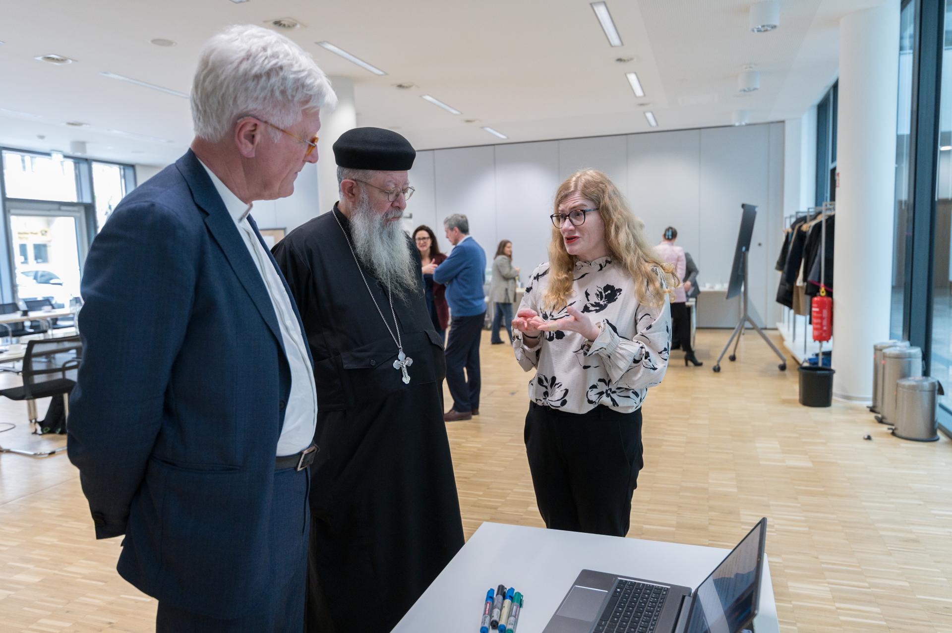 Kirkkojen maailmanneuvoston moderaattori keskuskomitean moderaattori Piispa Heinrich Bedford-Strohm sekä Isä Moussa (Moïse) Naguib, koptilainen ortodoksipappi keskustelevat Eeva Salosen kanssa, joka toimii Helsingin seurakuntayhtymän johtavana asiantuntijana.