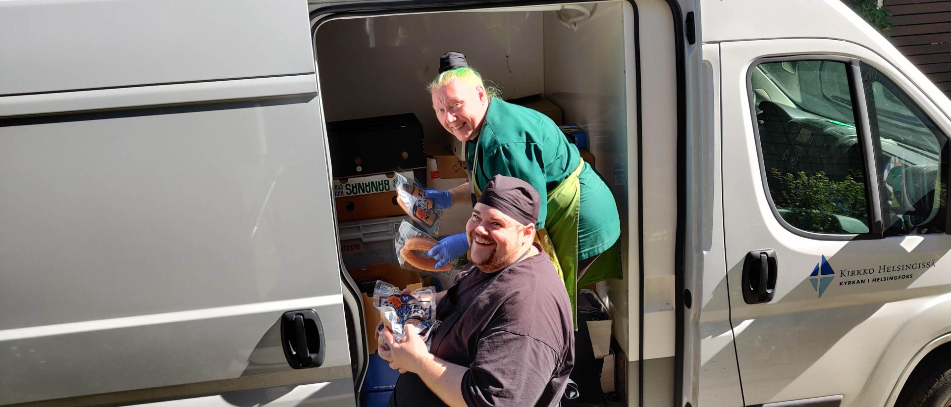 Kaksi työntekijää valitsee ruokatavaroita pakettiautosta käyttöön