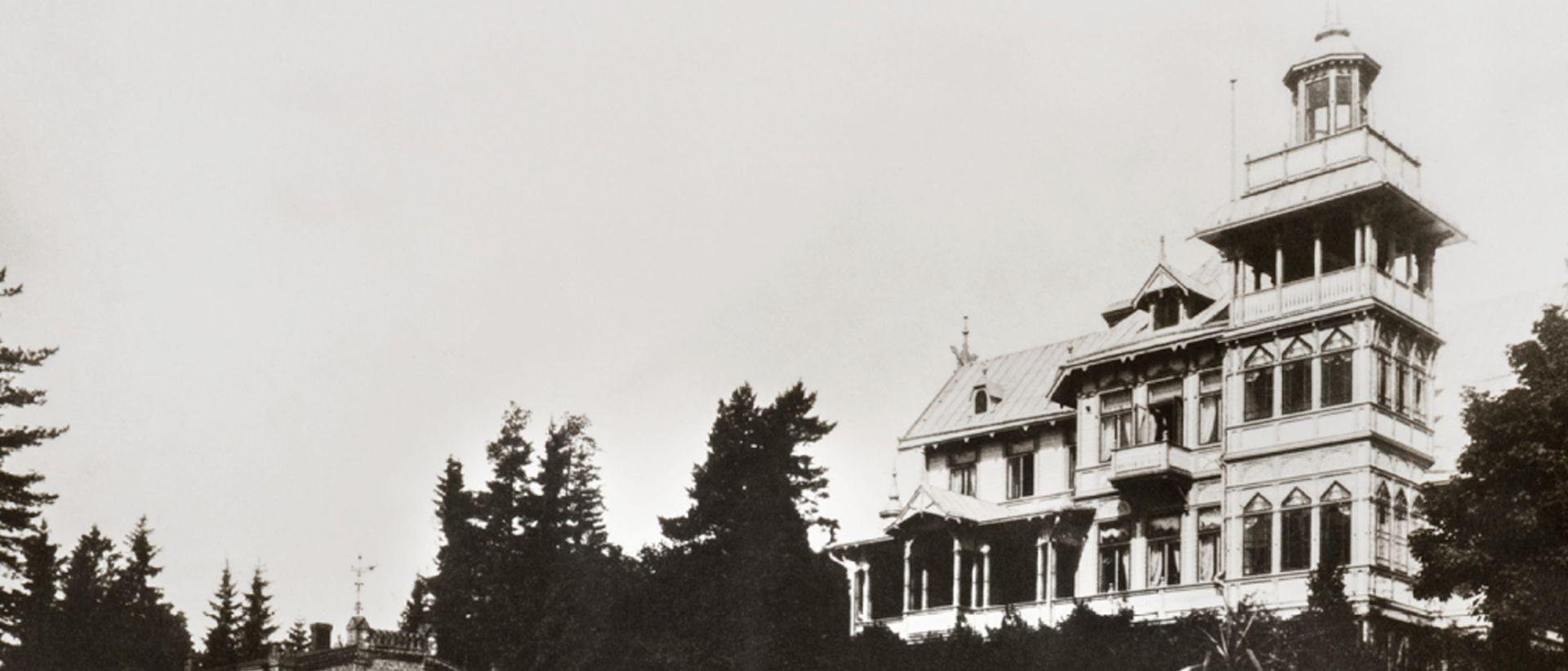 Mustavalkoinen kuva 1900-luvun taitteen Villa Edishemista. Pari kerrosta ja torni.