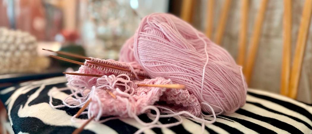 Vaaleanpunainen keskeneräinen käsityö tuolilla.