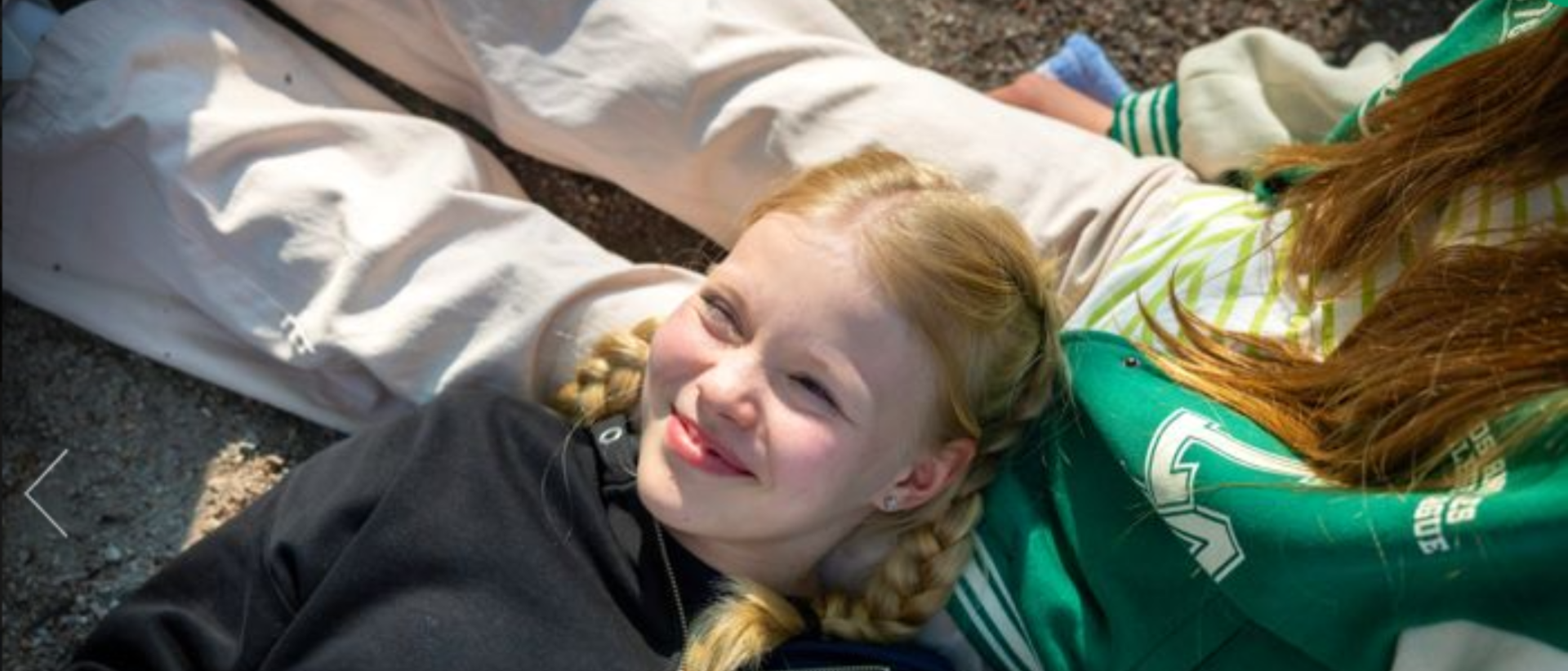 Teinitytt&ouml; makaa lattialla, p&auml;&auml; toisen nuoren jalkojen p&auml;&auml;ll&auml;.