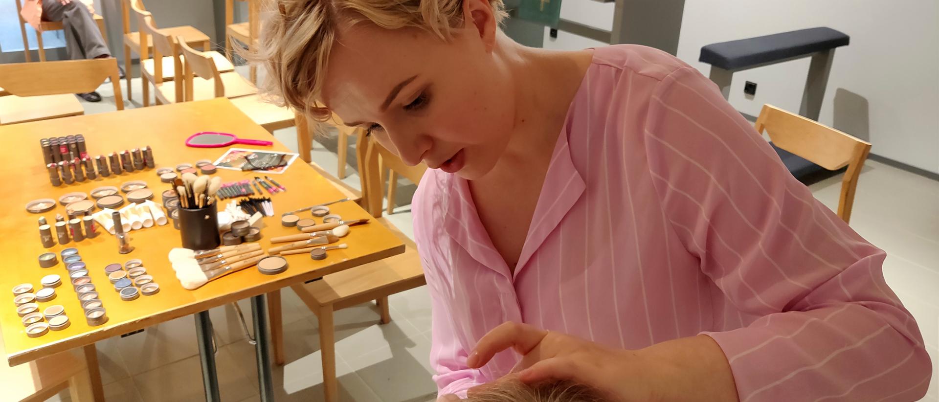 Kosmetologi Mira Heino tekee silmämeikkiä Puhkea kukkaan-illassa Katukappelissa