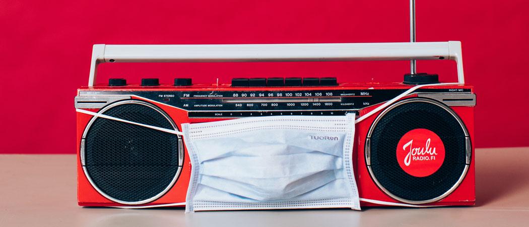 Kuvassa punainen radiovastaanotin, joka on puettu kertakäyttömaskiin ja jossa on tarra, jossa lukee: Jouluradio