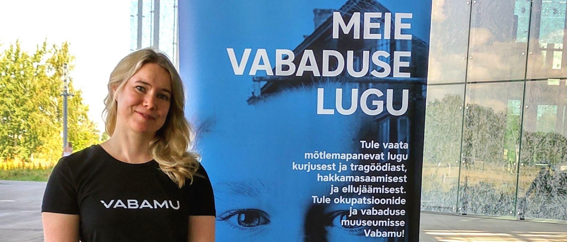 Tiedottaja Miska-Maria Välimäki Virossa kuvattuna opettajille suunnatuilla museomessuilla Tartossa Vabamu-museon ständin edessä.