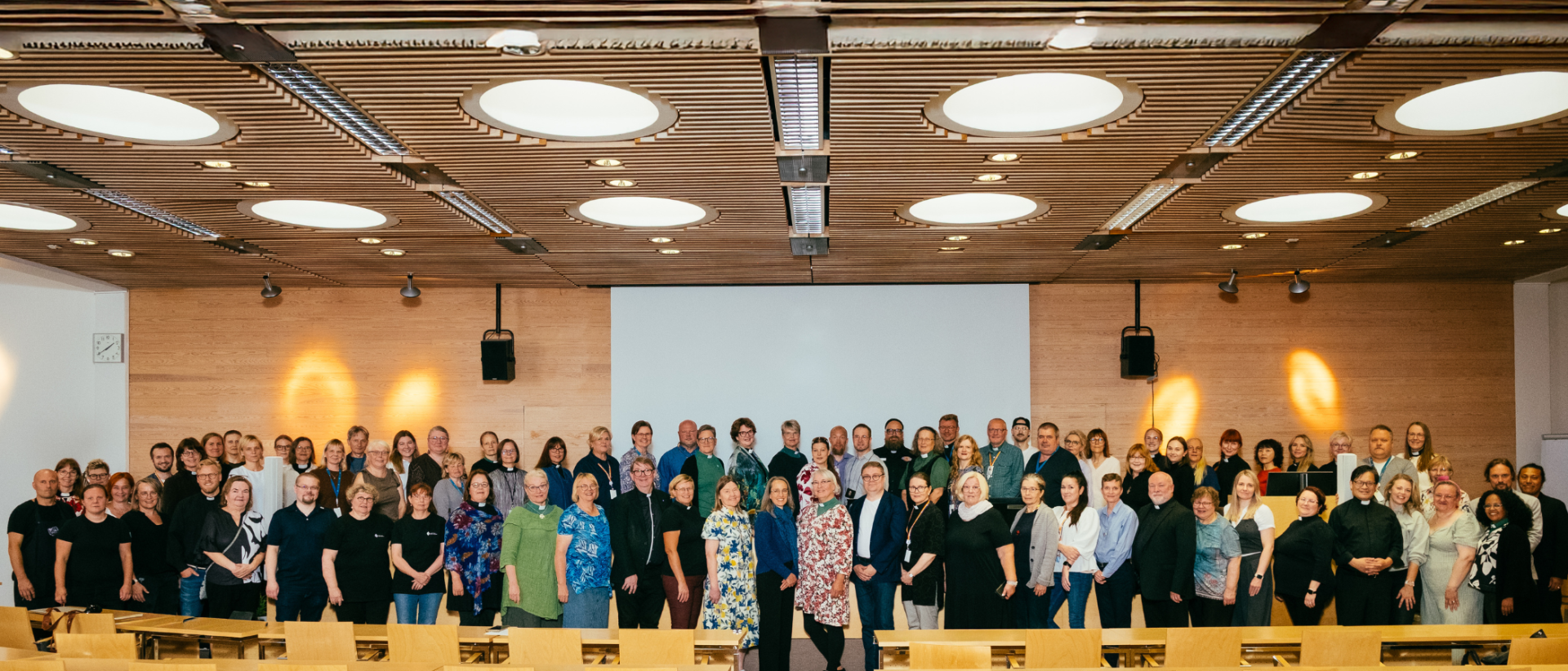 Noin sata Yhteisen srk-työn työntekijää ryhmäkuvassa luentosalissa