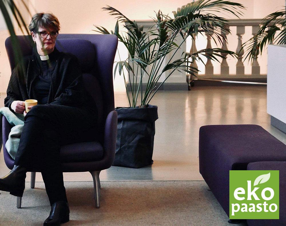 Lisa Eckell violetissa nojatuolissa viherkasvien keskellä