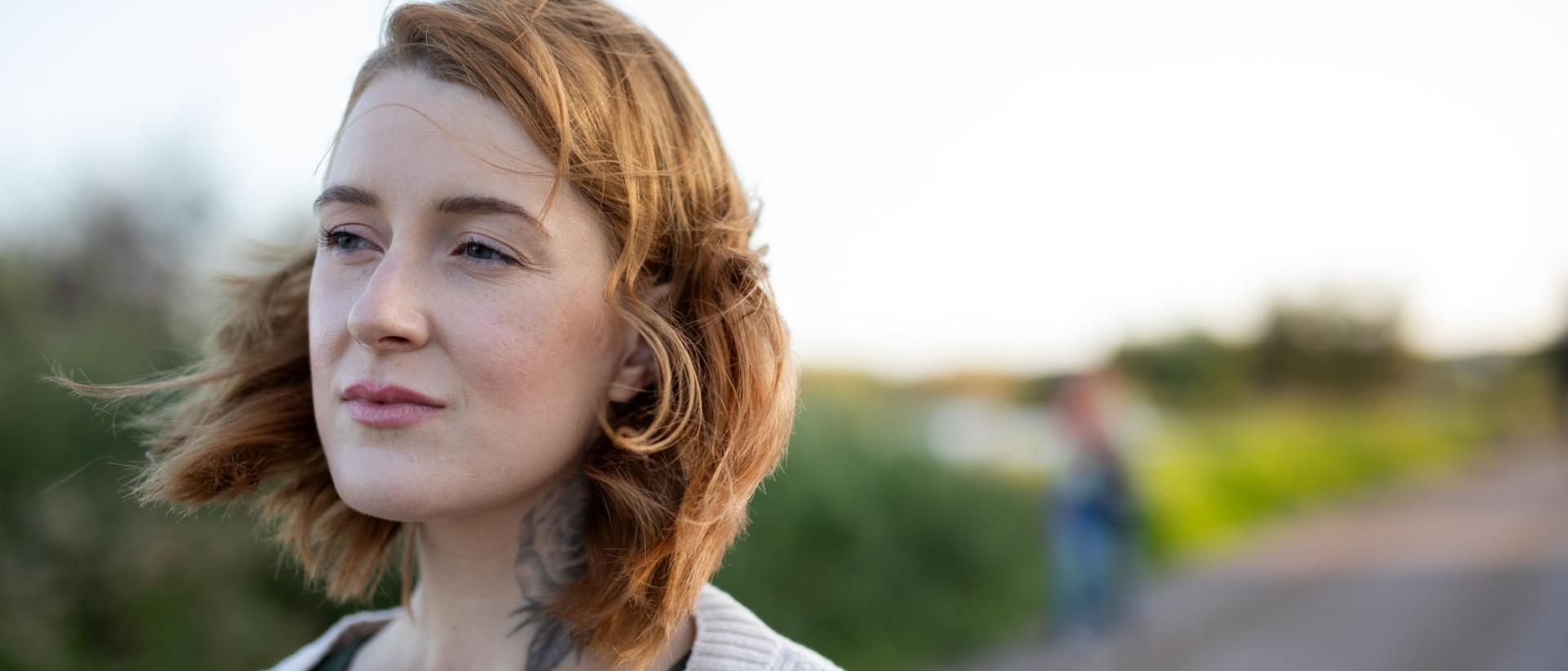 Lähikuvassa näinen joka katselee vasemmalle, takanaan avara, sumea maisema