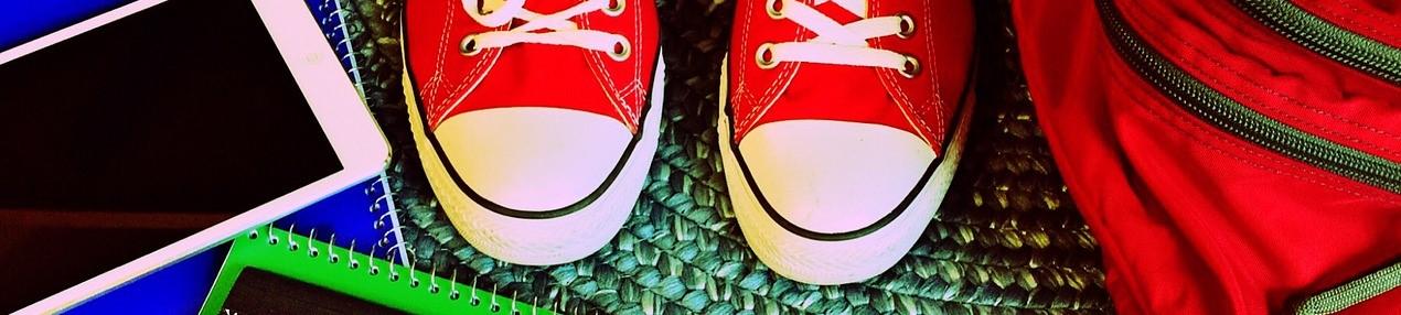 Kuvassa punaiset converset sek&auml; koulutarvikkeita. Kuvituskuva.