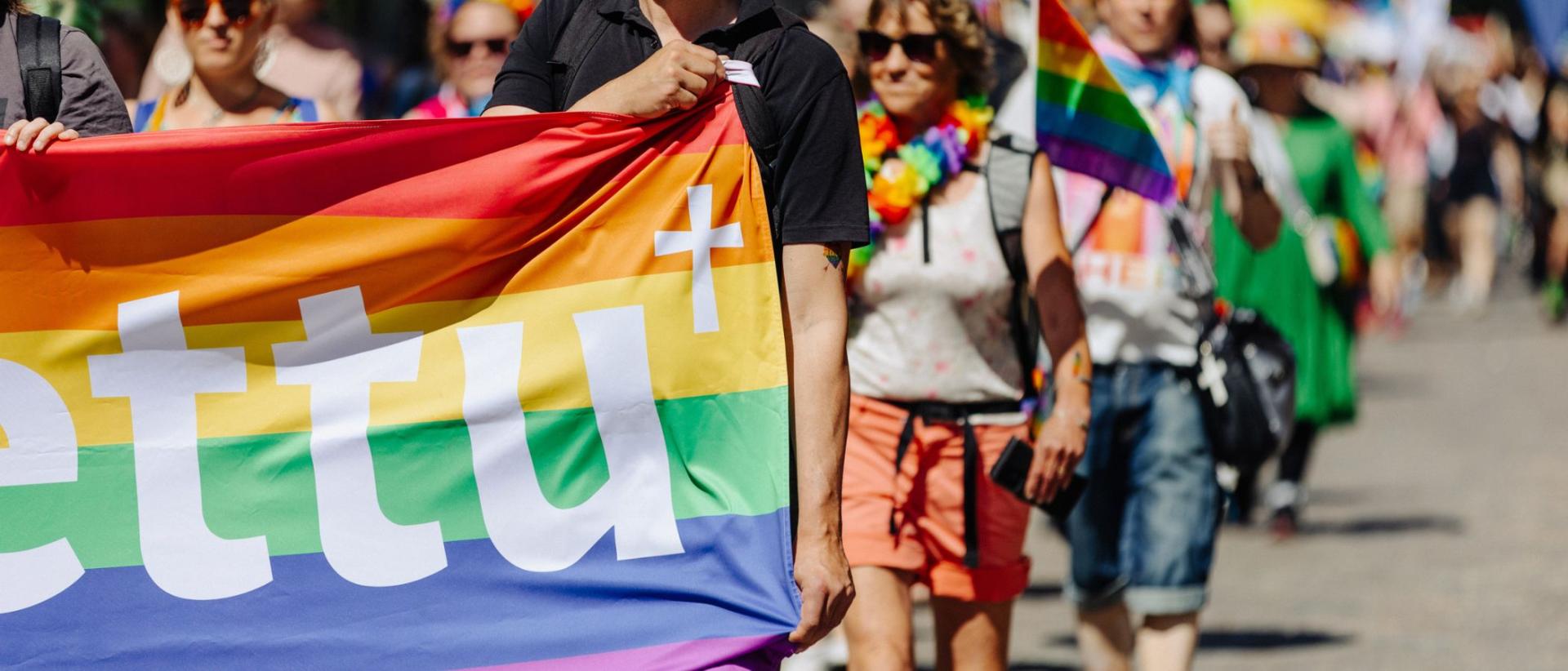 Ihmisi&auml; kantaa kulkueessa Pride-lippua