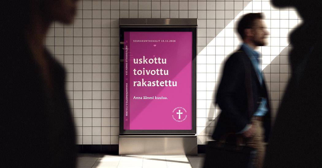 Ihmisiä kävelee alikulkutunnelissa, taustalla seurakuntavaalien mainos, jossa lukee: uskottu, toivottu, rakastettu