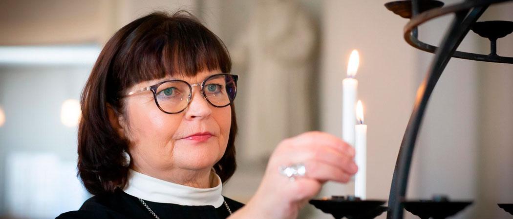 Kuvassa tuomiorovasti Marja Heltelä sytyttää kynttilää Tuomiokirkossa