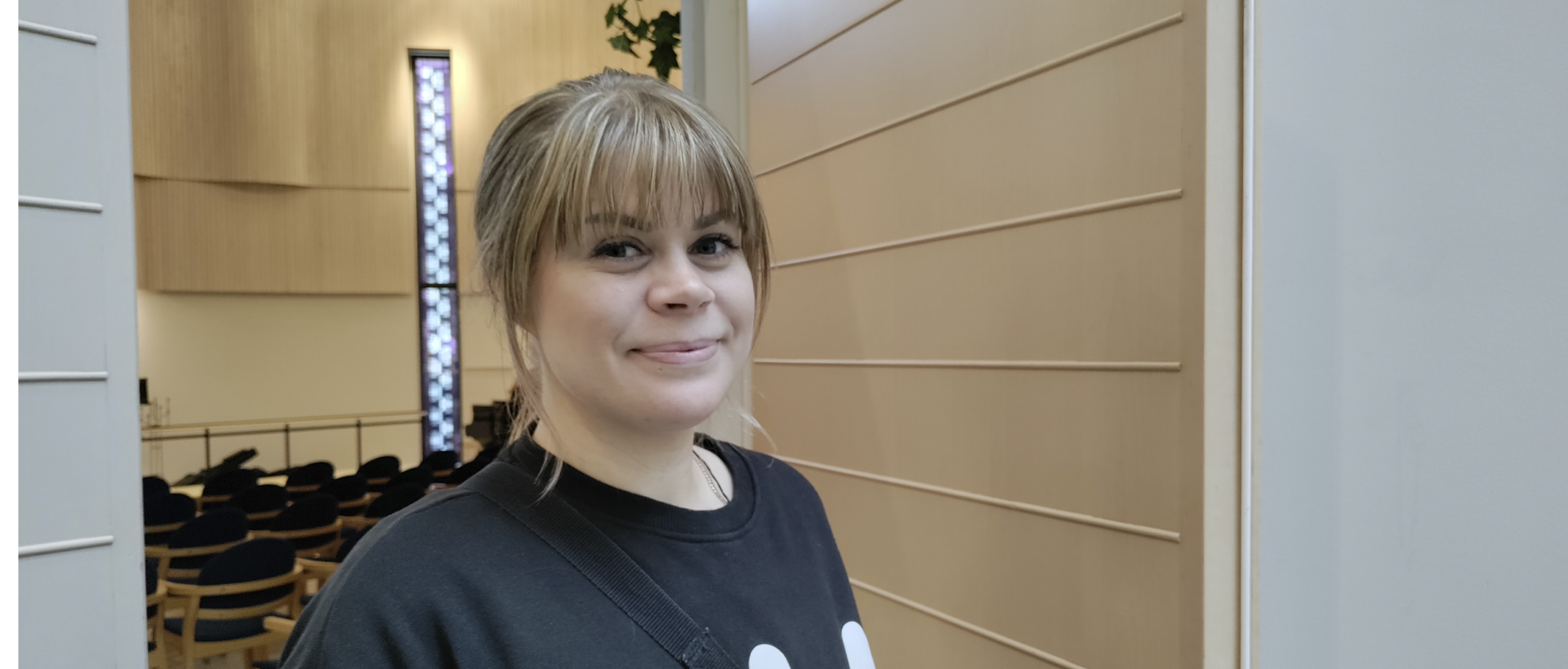 Diakoniaharjoittelija Janny Nieminen Myllypuron kirkon sisäoven edessä musta huppari päällä