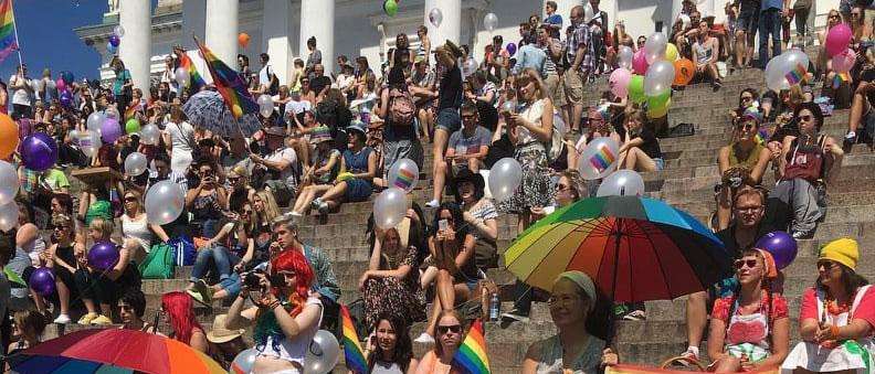 Kuvassa Pridekulkueeseen osallistuvaa väkeä Tuomiokirkon portailla.