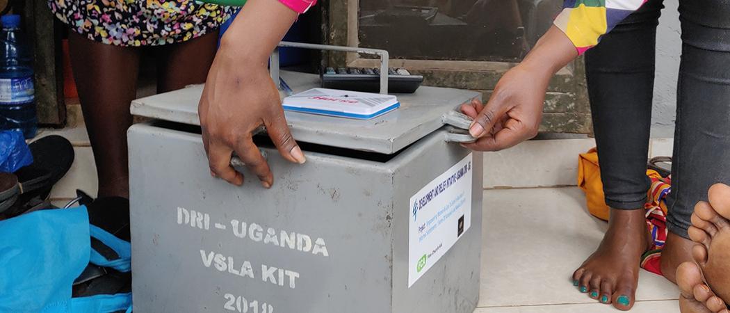 Kuvassa peltinen laatikko, jota avataan, laatikossa on naisten säästämiä rahoja Ugandassa