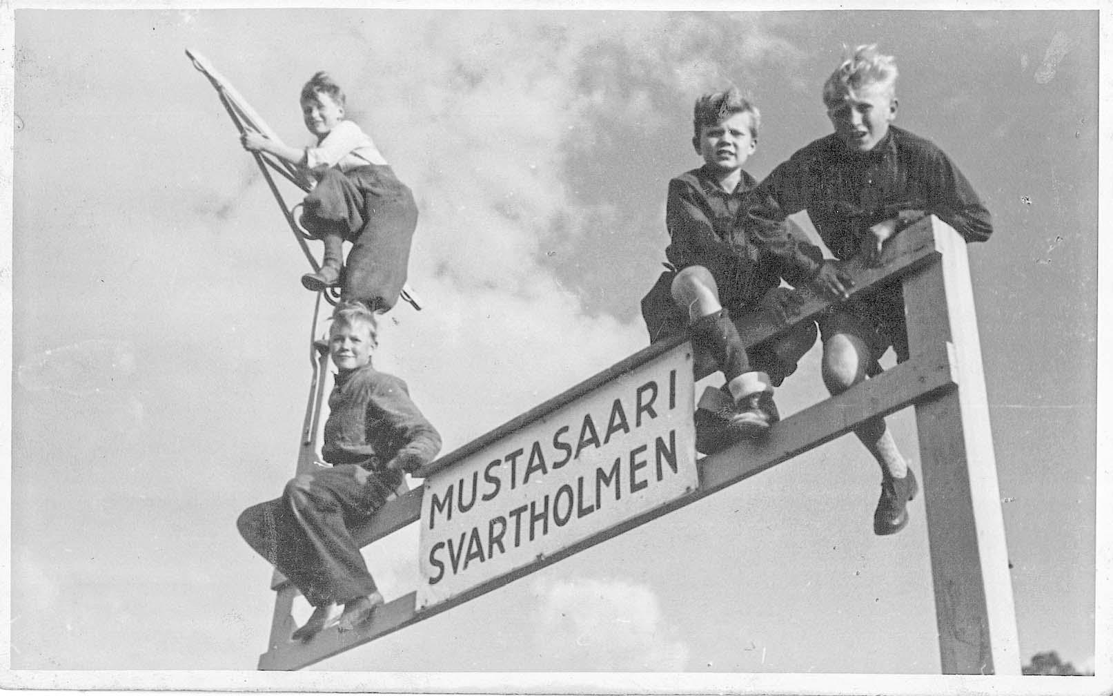 Vanha valokuva jossa pikkupoikia Mustasaaren laiturikyltin päällä
