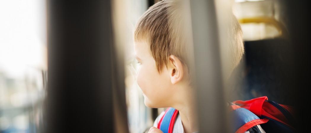 pieni poika katsoo linja-auton ikkunasta ulos ja kasvot eivät näy
