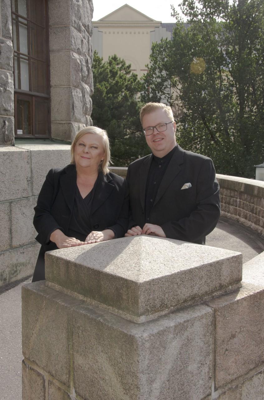 Kallion Kantaattikuoron Anu Kinnunen ja kuoroa johtava kanttori Tommi Niskala kuvattuna Kallion kirkon edessä.