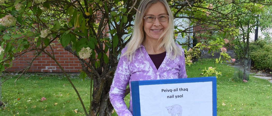 Tuula Kosonen kuvattuna Vuosaaren kirkon pihalla. Kädessään hänellä on aken kielinen lasten koulukirja.