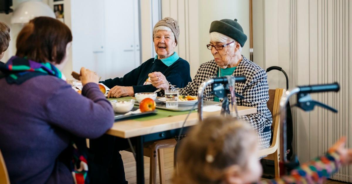 Kolme eläkeläisnaista istuu syömässä ruokapöydän ääressä