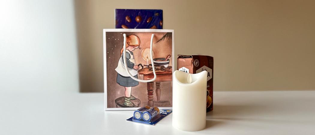 Kuva jossa lahjakassi, led-kynttilä paristoineen, kahvipaketti ja suklaarasia