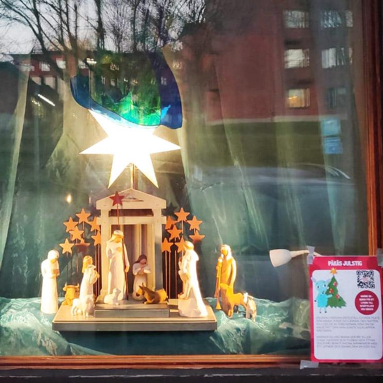 Ett fönster med en julkrubba i. En stjärna lyser ovanför krubban.