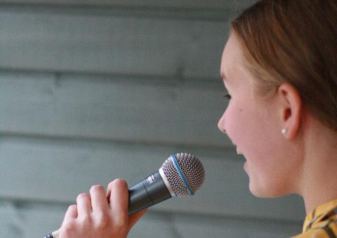 Nainen laulaa mikrofoniin.