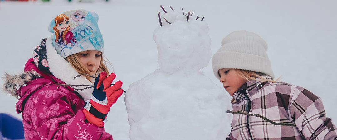 Kaksi lasta rakentaa lumiukkoa kuva: unsplash