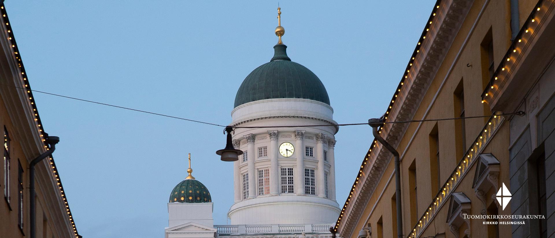 Kuvassa Kauppatorilta päin kuvattuna jouluvalaistujen talojen välistä näkyvän Tuomiokirkon tornia ja yksi kupoleista.